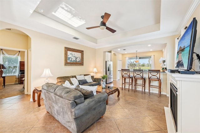 living area featuring a tray ceiling, arched walkways, healthy amount of natural light, ceiling fan, and recessed lighting