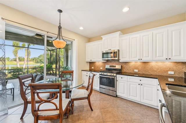 kitchen with appliances with stainless steel finishes, hanging light fixtures, white cabinetry, tasteful backsplash, and a sink