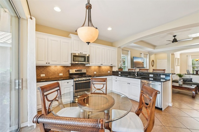 kitchen featuring appliances with stainless steel finishes, a peninsula, a sink, healthy amount of natural light, and recessed lighting