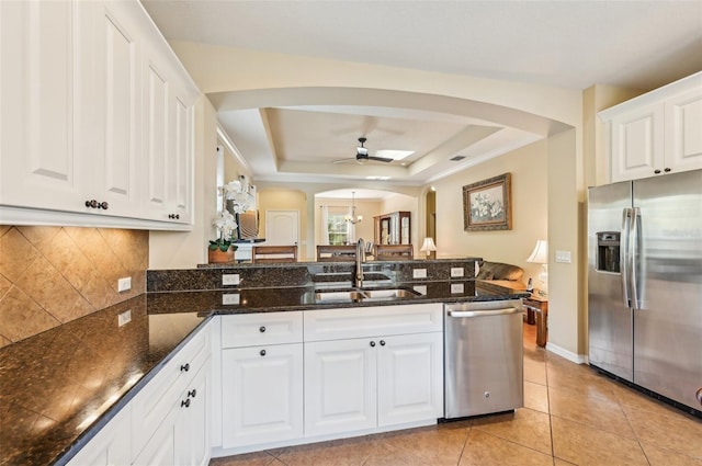 kitchen featuring appliances with stainless steel finishes, arched walkways, a ceiling fan, a peninsula, and a sink