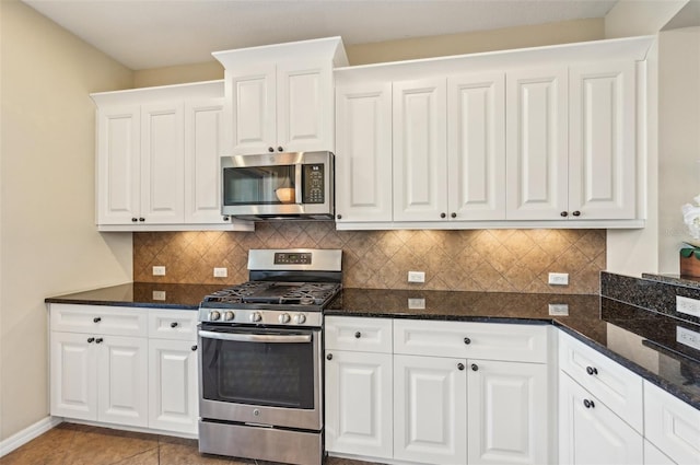 kitchen featuring stainless steel appliances, white cabinetry, and backsplash