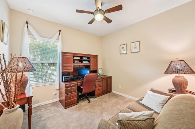 office area with light colored carpet, a ceiling fan, and baseboards
