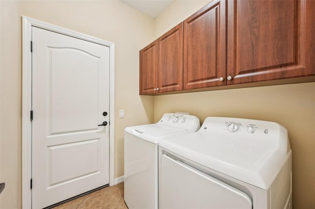 laundry room featuring washer and dryer, cabinet space, and light tile patterned floors