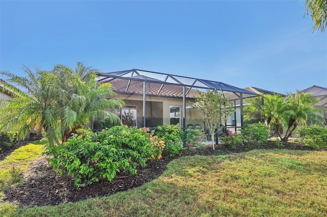 back of property with a yard and glass enclosure
