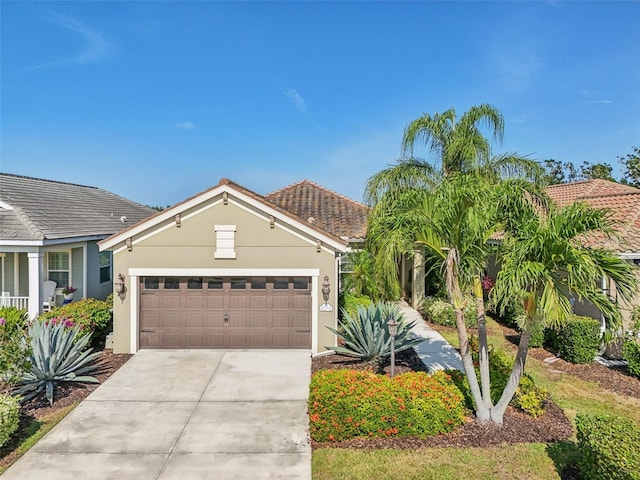 view of front of property with stucco siding, concrete driveway, an attached garage, and a tile roof