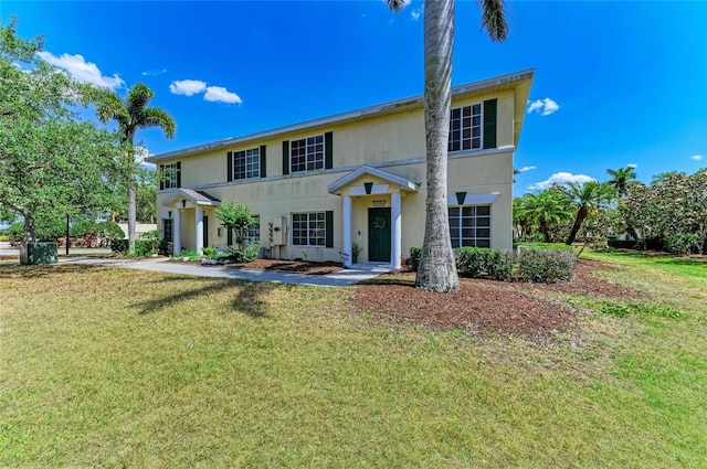 colonial inspired home featuring stucco siding and a front lawn