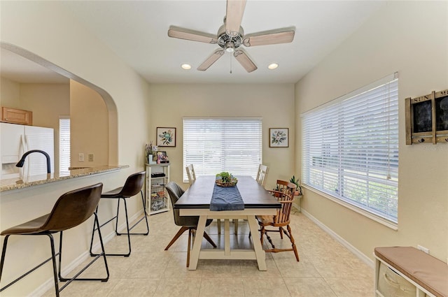 dining room with baseboards, arched walkways, a ceiling fan, and a wealth of natural light