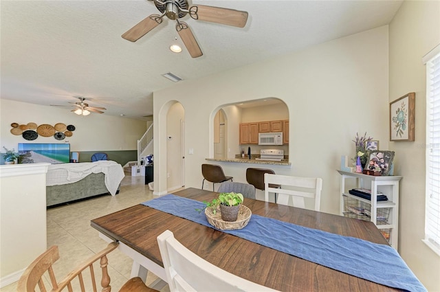 dining space featuring arched walkways, ceiling fan, recessed lighting, and light tile patterned floors