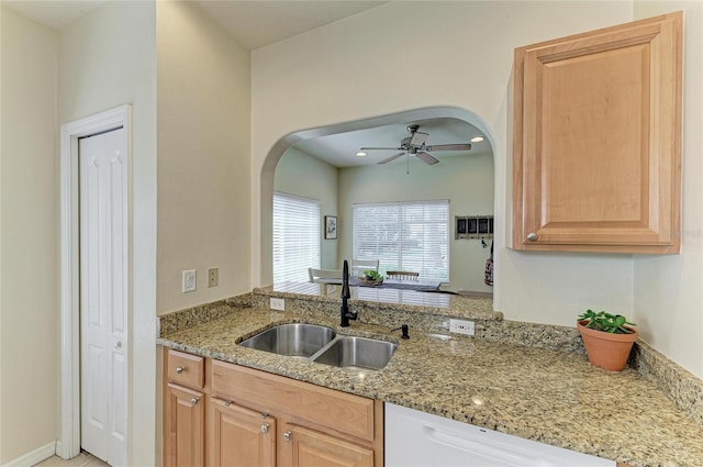 kitchen featuring a ceiling fan, arched walkways, light stone countertops, dishwasher, and a sink