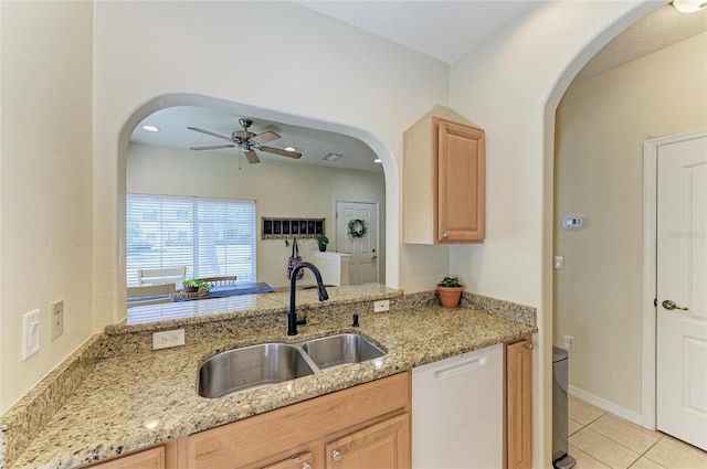 kitchen with dishwasher, a sink, light tile patterned floors, light stone counters, and light brown cabinets