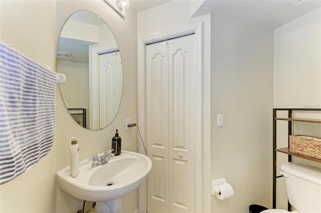 bathroom featuring a sink, toilet, and visible vents