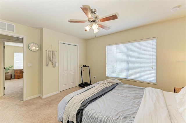bedroom with visible vents, a closet, baseboards, ceiling fan, and light colored carpet