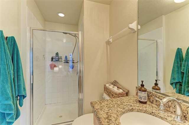 full bath with vanity, a stall shower, and toilet