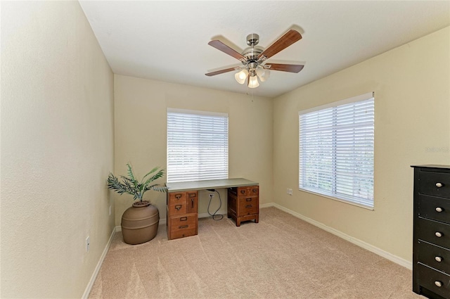 office space with baseboards, light carpet, and a ceiling fan