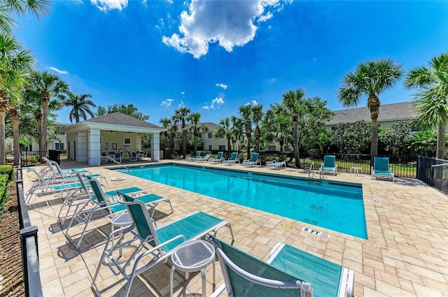 community pool with fence and a patio area