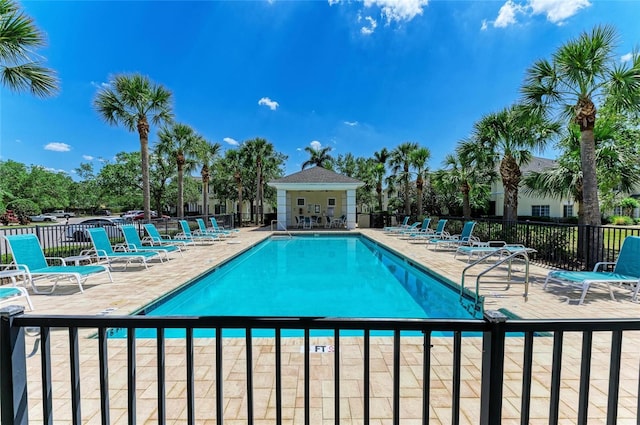 community pool with a patio and fence
