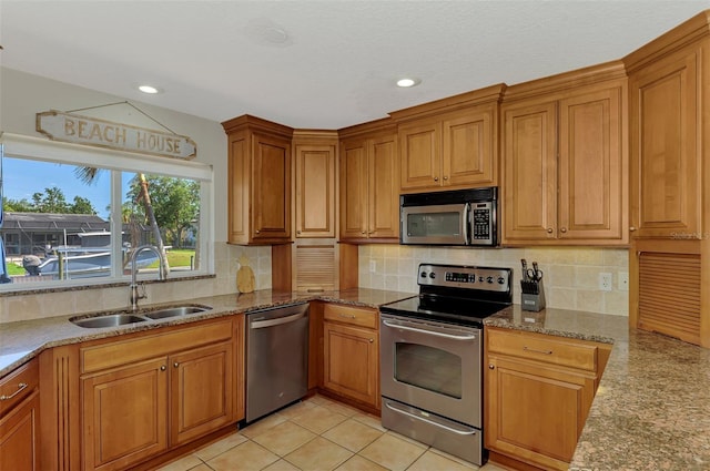 kitchen with recessed lighting, light stone countertops, appliances with stainless steel finishes, and a sink