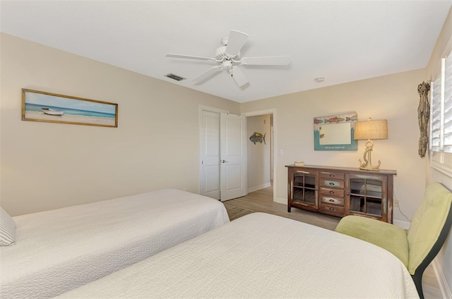 bedroom with baseboards, a ceiling fan, visible vents, and wood finished floors