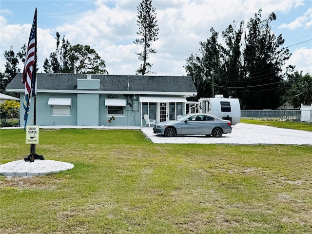 view of front of home with a front yard, driveway, a shingled roof, and fence