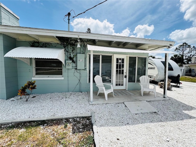 rear view of property featuring a porch and concrete block siding