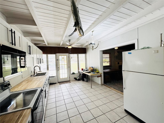 kitchen with freestanding refrigerator, butcher block counters, black microwave, beamed ceiling, and electric range