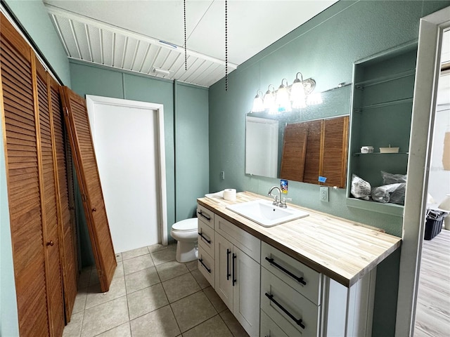 bathroom with a closet, toilet, tile patterned flooring, and vanity