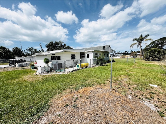 rear view of property featuring a yard, fence, and a gate