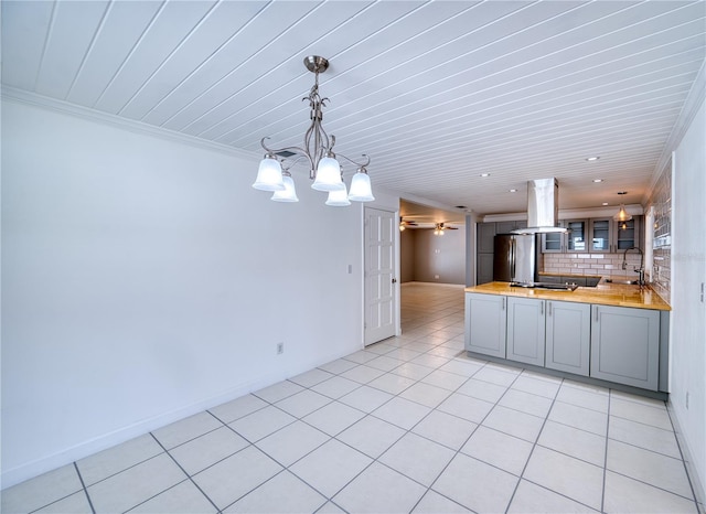 kitchen featuring gray cabinets, island range hood, freestanding refrigerator, a peninsula, and butcher block counters