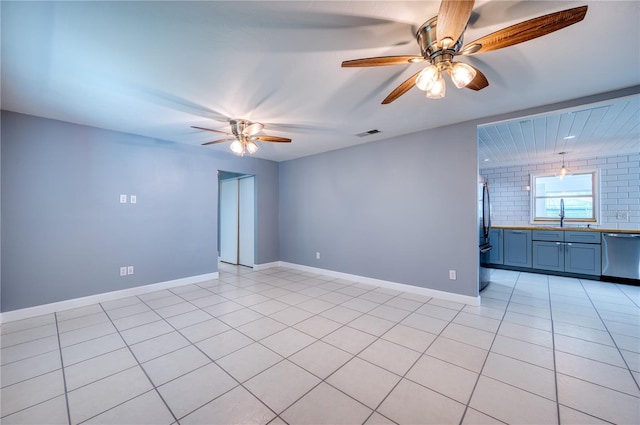 spare room with light tile patterned floors, a ceiling fan, a sink, and visible vents