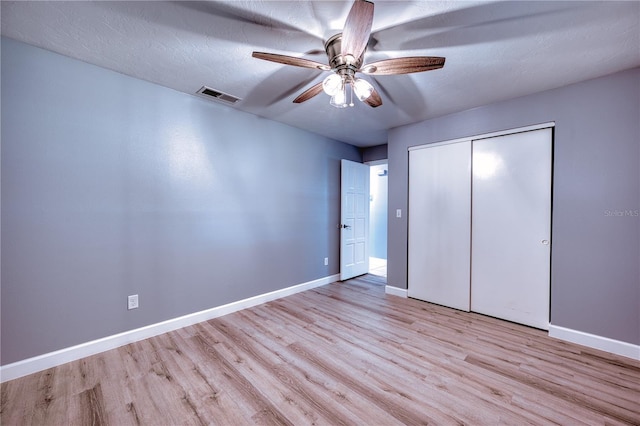 unfurnished bedroom with baseboards, visible vents, wood finished floors, and a closet