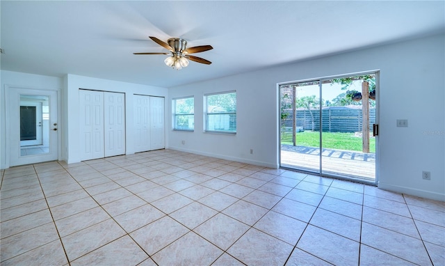 unfurnished bedroom with access to outside, two closets, a ceiling fan, baseboards, and light tile patterned floors
