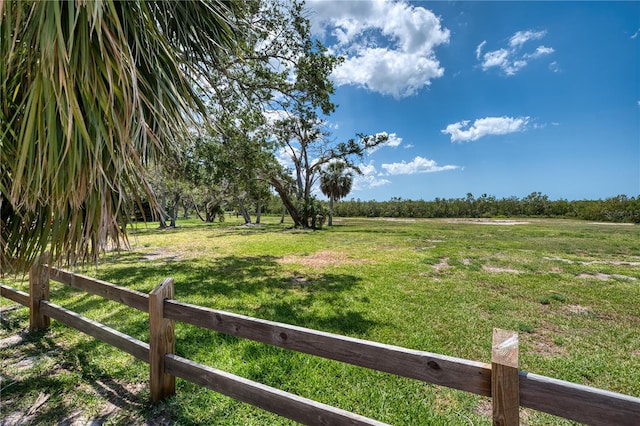 view of yard with fence and a rural view