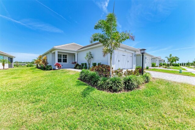 view of front of home featuring a garage, stucco siding, driveway, and a front yard