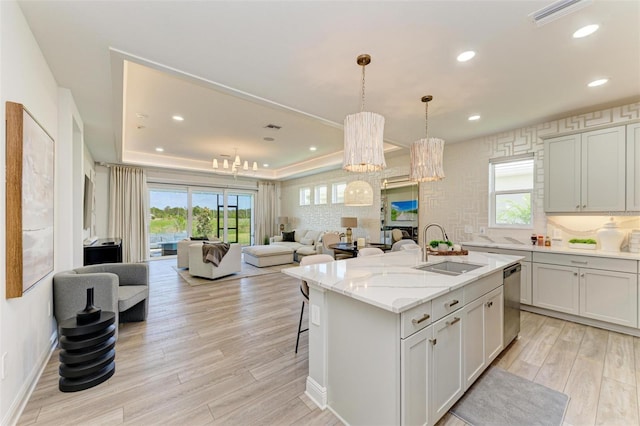 kitchen with a sink, dishwasher, a chandelier, light wood-style flooring, and open floor plan