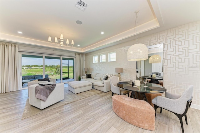 living room with visible vents, light wood-style flooring, and a raised ceiling