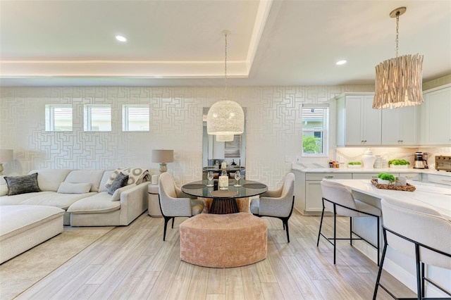 living room with a raised ceiling, recessed lighting, and light wood-style flooring