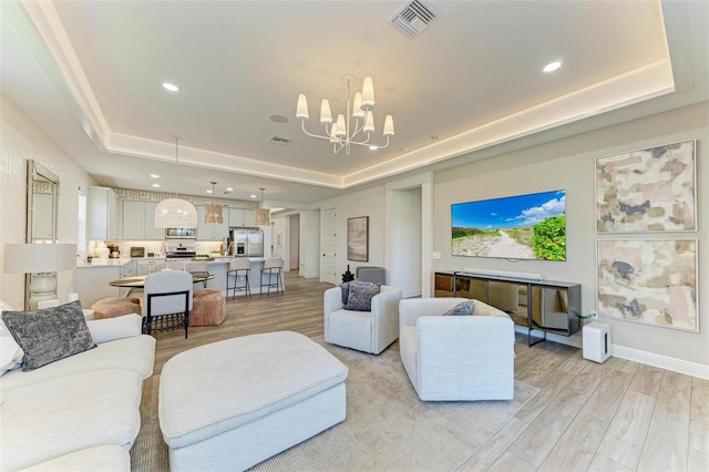 living area featuring visible vents, recessed lighting, a raised ceiling, a chandelier, and light wood-style flooring