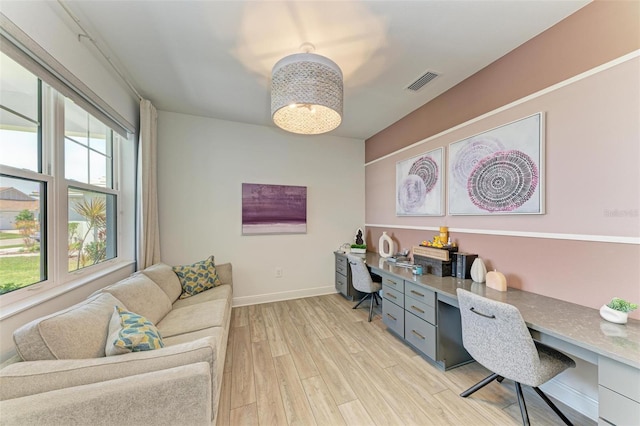 office area featuring light wood-style floors, baseboards, built in desk, and visible vents
