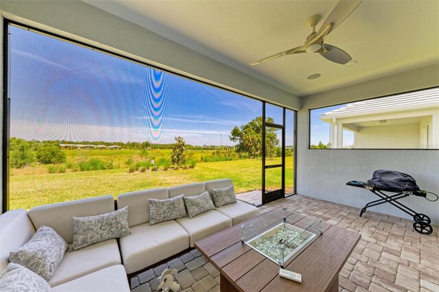 sunroom featuring ceiling fan and an outdoor living space with a fire pit