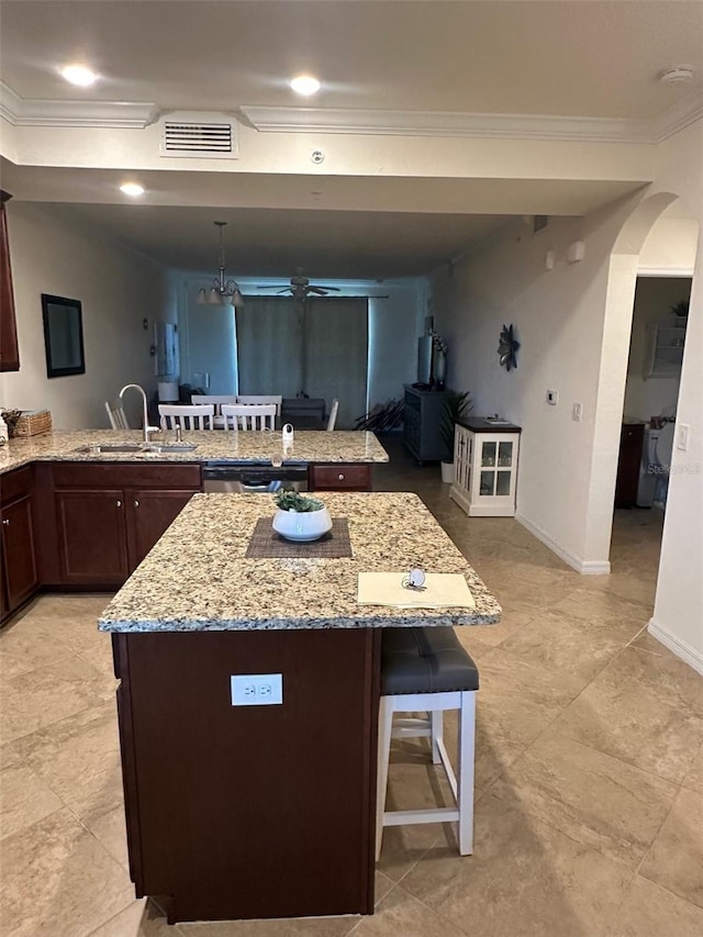 kitchen with crown molding, visible vents, a peninsula, a kitchen bar, and a sink