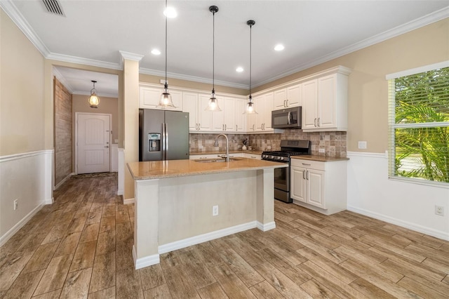 11634 Piedmont Park Xing, Bradenton, FL 34211 - kitchen with appliances with stainless steel finishes, a sink, light wood-style floors, white cabinets, and ornamental molding