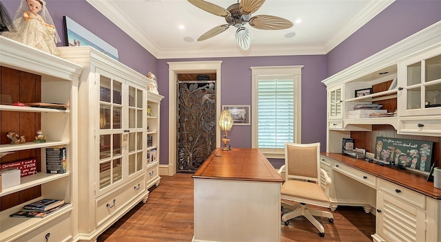 home office featuring a ceiling fan, built in desk, dark wood-type flooring, and crown molding