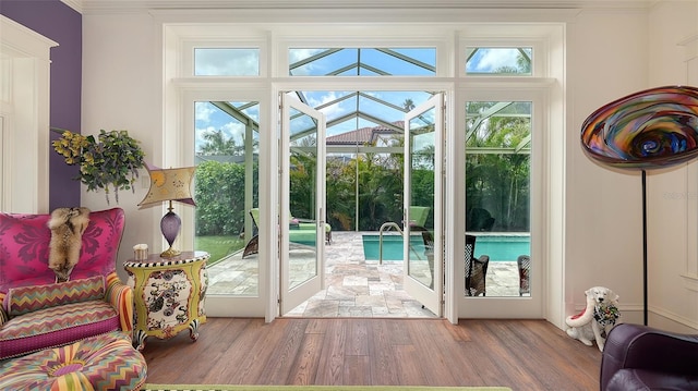 entryway with wood finished floors, ornamental molding, a sunroom, and healthy amount of natural light
