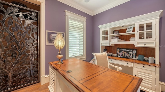 home office with light wood finished floors, crown molding, and built in study area