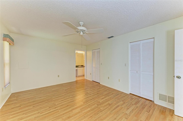 interior space with two closets, a textured ceiling, visible vents, and light wood-style floors