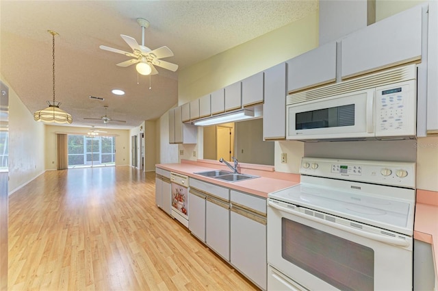kitchen with a sink, white appliances, a ceiling fan, open floor plan, and light wood-type flooring