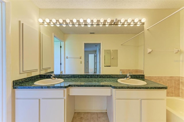 full bath with double vanity, a bathtub, a sink, and tile patterned flooring