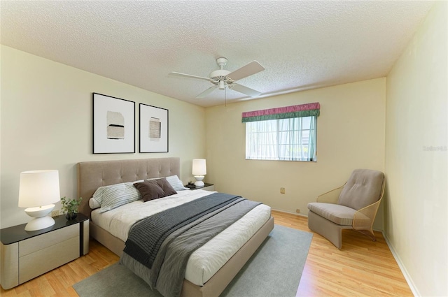 bedroom with baseboards, a textured ceiling, ceiling fan, and light wood-style flooring