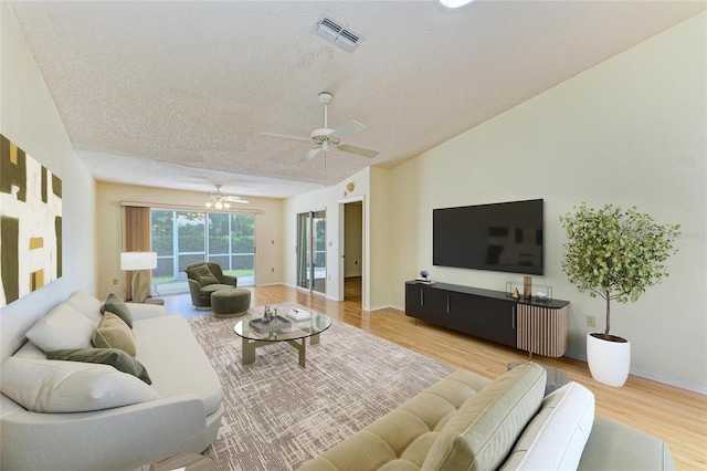 living area with ceiling fan, light wood-type flooring, a textured ceiling, and visible vents