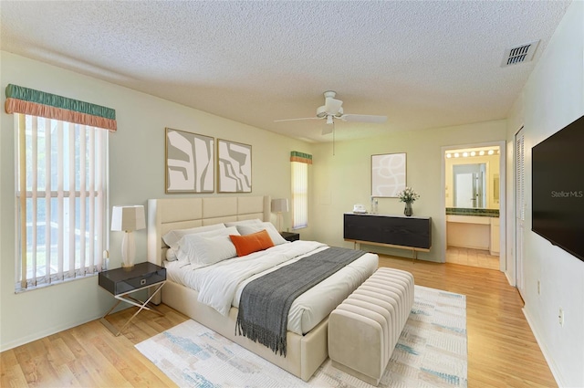 bedroom featuring visible vents, a textured ceiling, and multiple windows